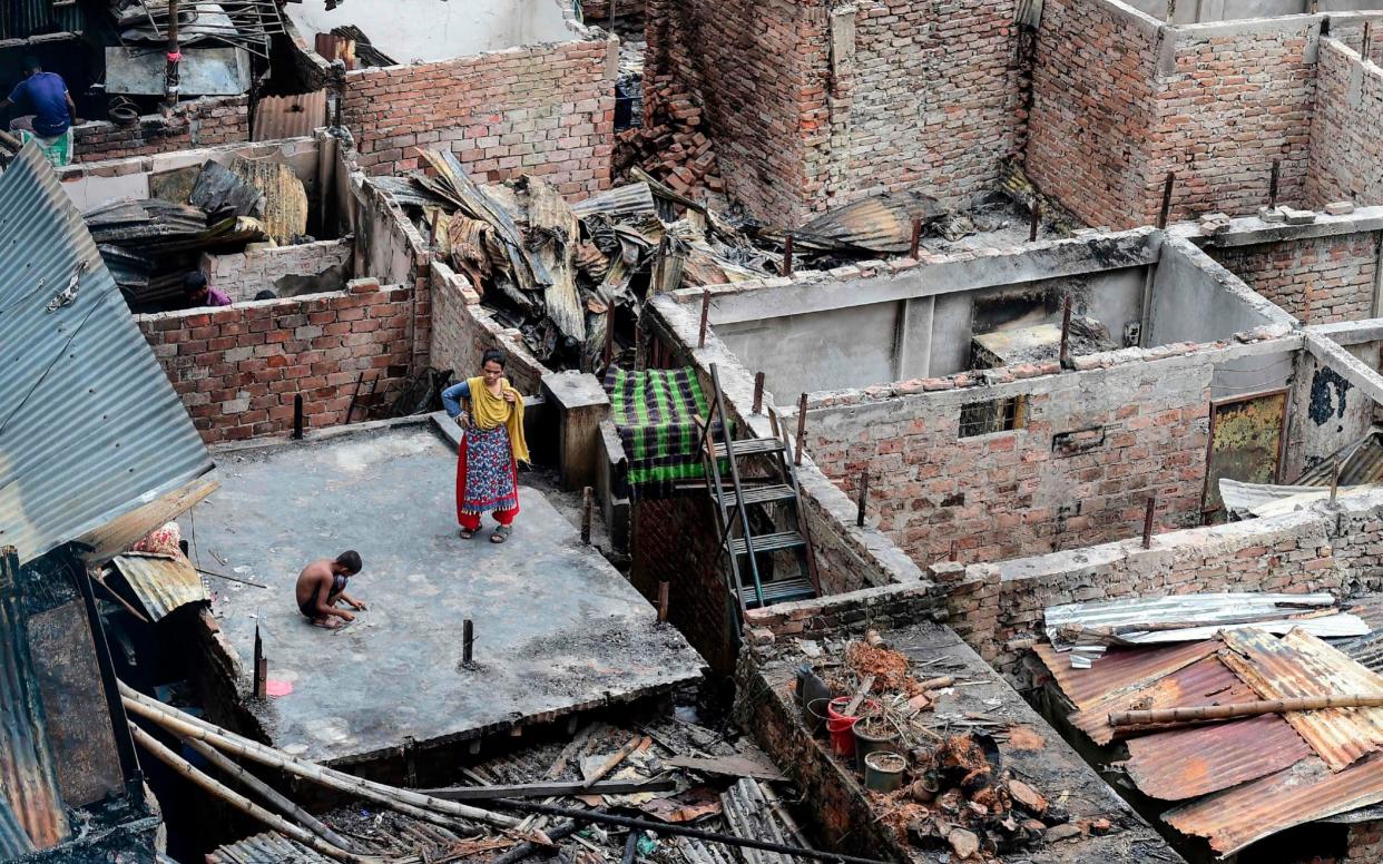 A child plays on a roof of a burnt house in a slum in Dhaka - AFP