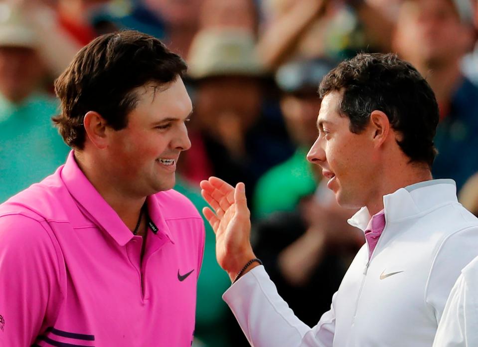 In happier times, Patrick Reed, left, is congratulated by Rory McIlory after Reed's 2018 win at the Masters in Augusta, Ga. Reed has become a polarizing figure in golf, having left the PGA Tour for the more lucrative — and controversial — LIV Tour.