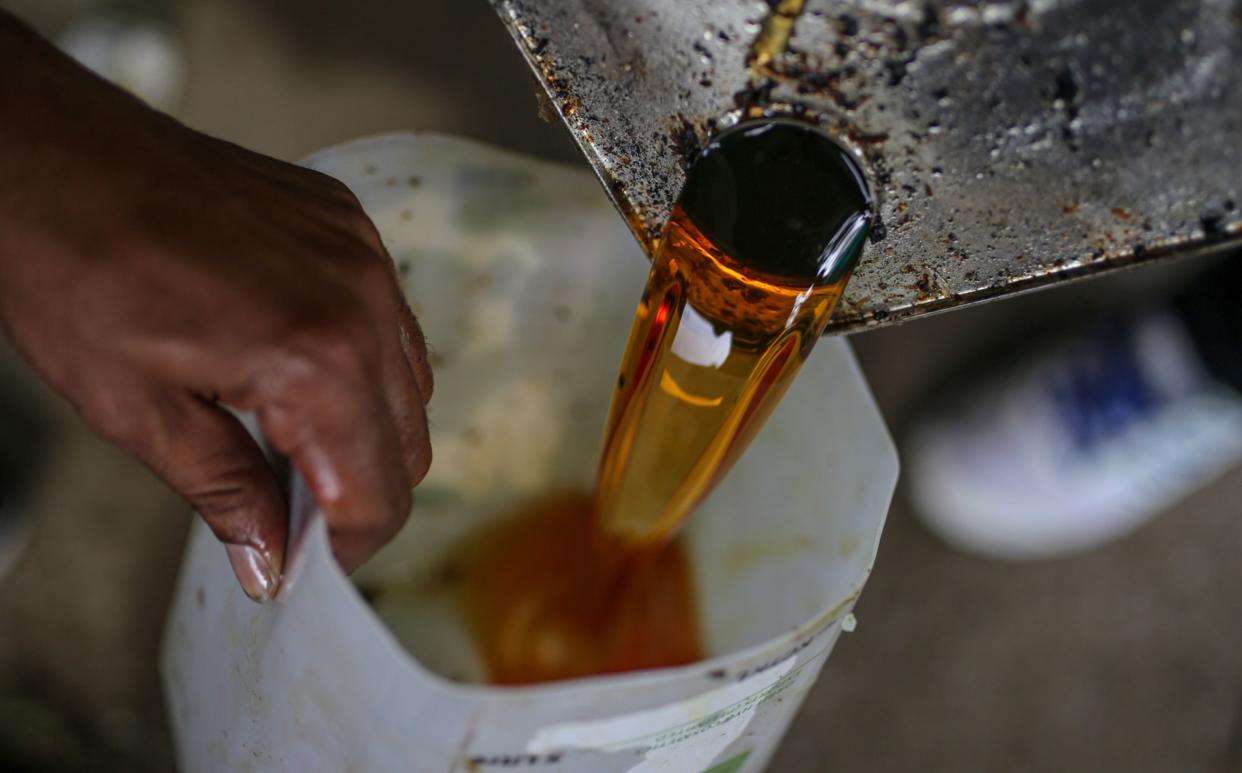 Pyarelal, left and Praveen Upreti, field coordinator, Social Development For Communities Foundation, collect used cooking oil at a restaurant in Dehradun, India, on Friday, Oct. 7, 2022. Photographer: Dhiraj Singh/Bloomberg