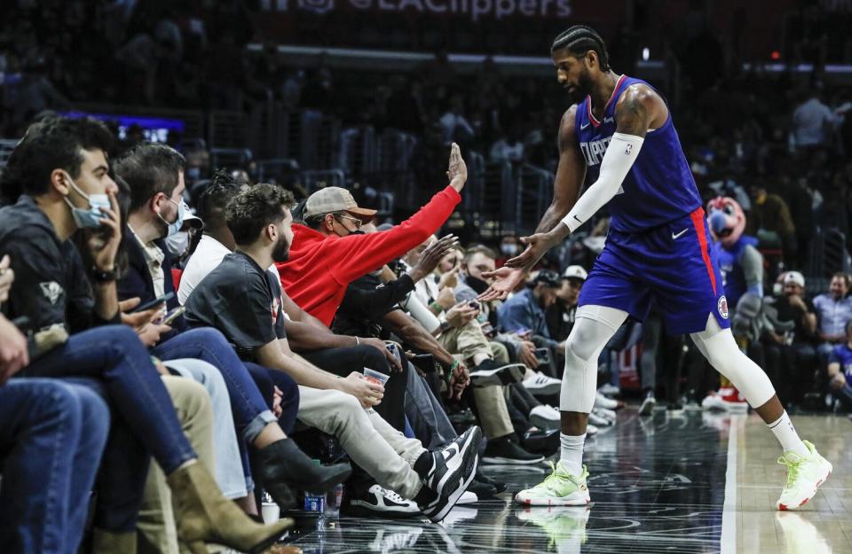 Clippers forward Paul George slaps hands with a fan.