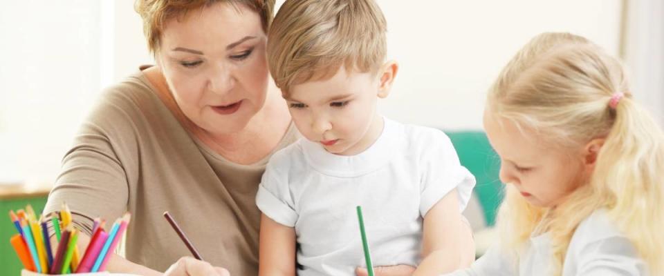 Happy senior woman painting together with grandchildren at home