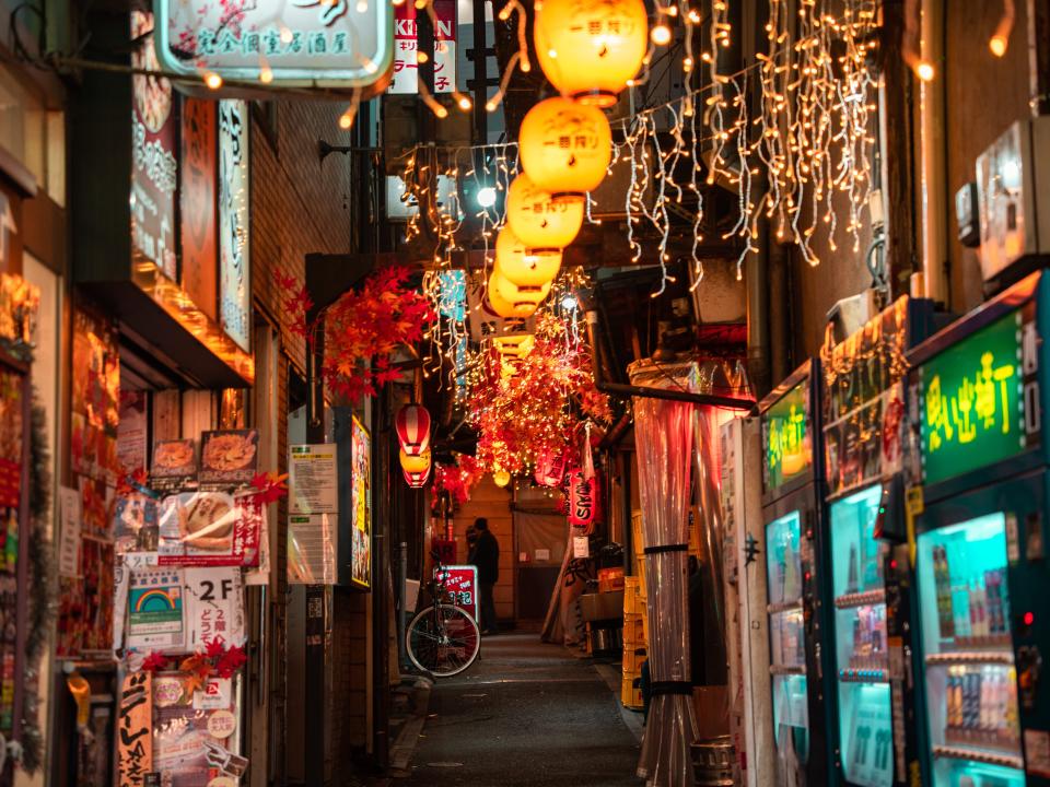 A brightly-lit street at night, decorated with lanterns and strings of lights.