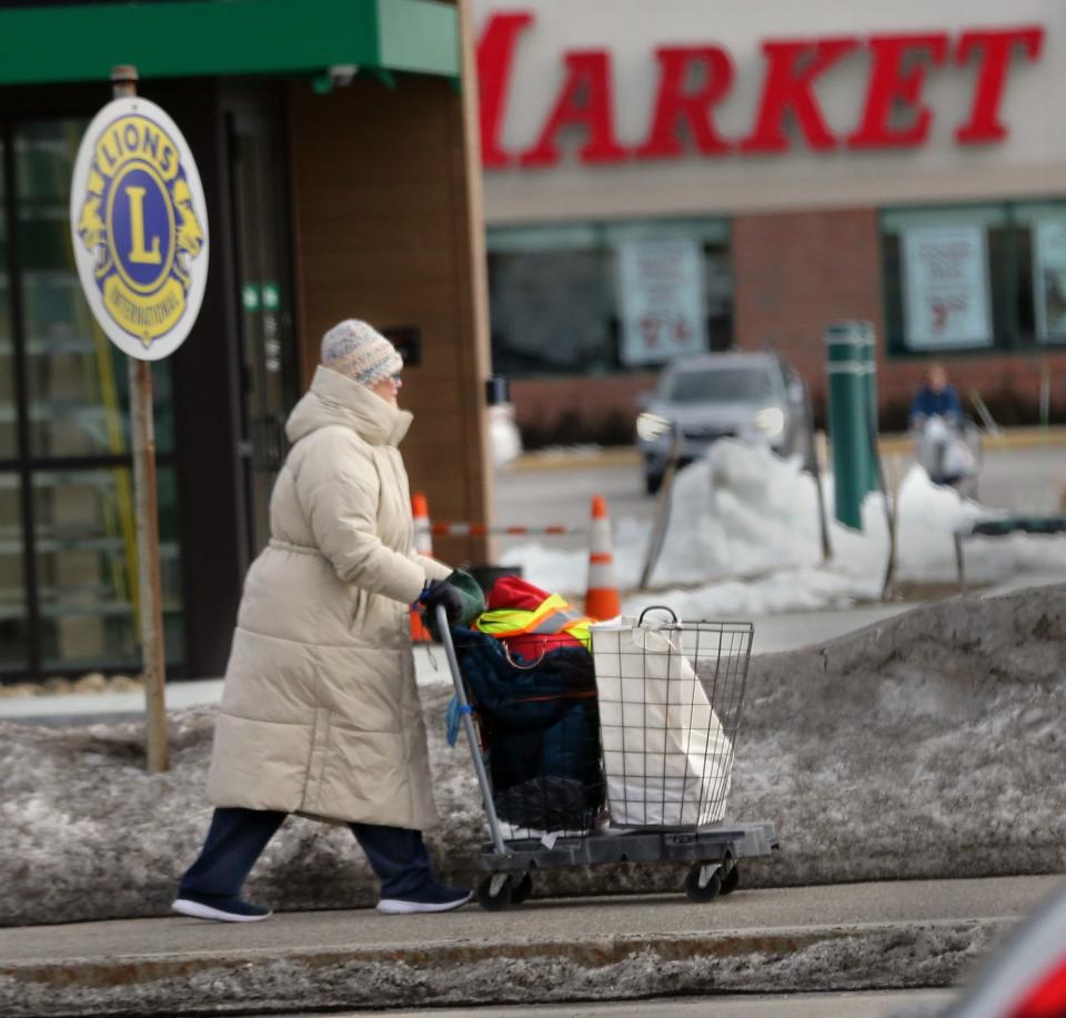 A woman bundled in a long coat pushes her shopping basket a long High Street in Somersworth Feb. 2, 2023, ahead of the arrival of extreme cold weather expected Friday and Saturday.