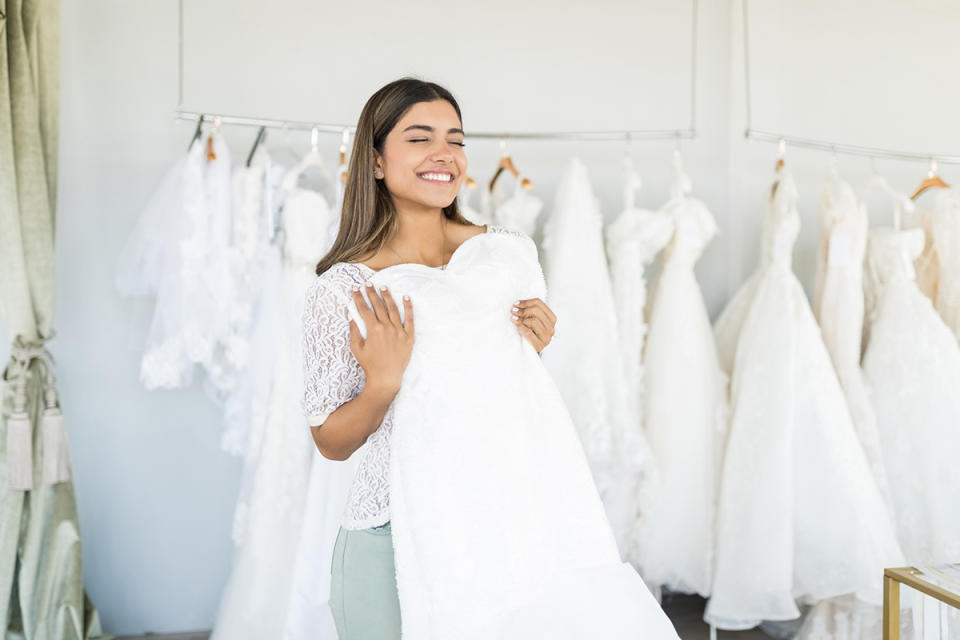 Satisfied female customer holding her beautiful wedding dress in bridal shop