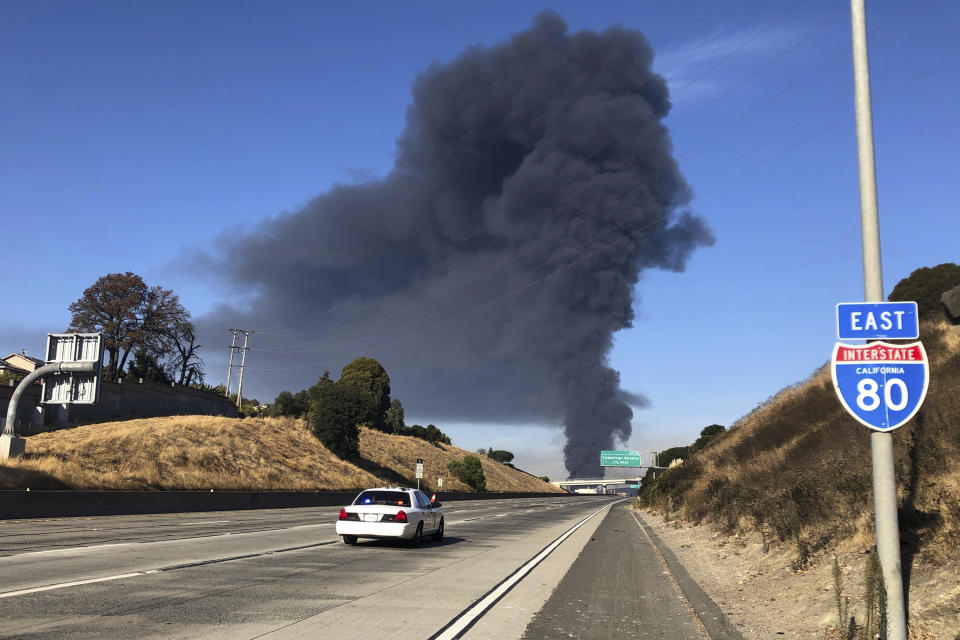 Interstate 80 is closed as a fire at an oil storage facility burns in the background Tuesday, Oct. 15, 2019, in Rodeo, Calif. A fire burning at NuStar Energy LP facility in Crockett, Calif., in the San Francisco Bay Area prompted a hazardous materials emergency that led authorities to order the residents of two communities, including Rodeo, to stay inside with all windows and doors closed. Contra Costa Fire Department spokesman Steve Hill said that an hour into battling the blaze, firefighters seemed to be making progress and were continuing to keep adjacent tanks cooled with water. (AP Photo/Ben Margot)
