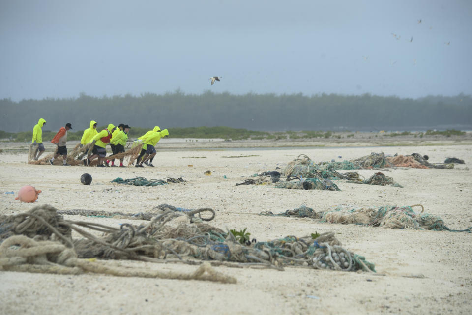 In this April 9, 2021 photo provided by Matthew Chauvin, workers with the Papahanaumokuakea Marine Debris Project drag fishing nets off the beach of Midway Atoll in the Northwestern Hawaiian Islands. A crew has returned from the remote Northwestern Hawaiian Islands with a boatload of marine plastic and abandoned fishing nets that threaten to entangle endangered Hawaiian monk seals and other marine animals on the tiny, uninhabited beaches stretching for more than 1,300 miles north of Honolulu. (Matthew Chauvin, Papahanaumokuakea Marine Debris Project via AP)