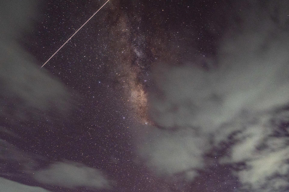 a streak of white light passes in front of the stars in the night sky