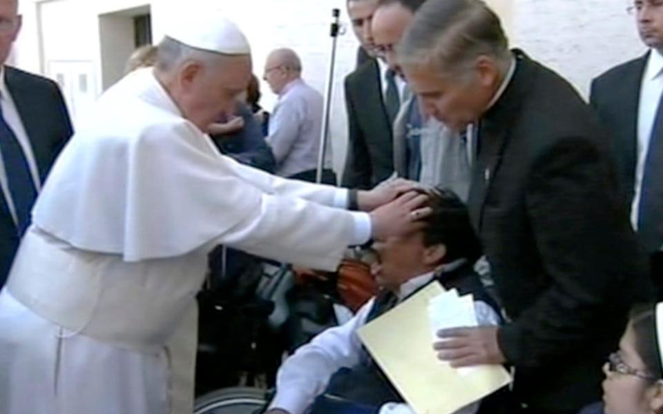 Pope Francis lays his hands on the head of a young man in May, 2013, after celebrating Mass in St. Peter's Square. There was widespread speculation that he had performed an exorcism to free the man from the devil - AP