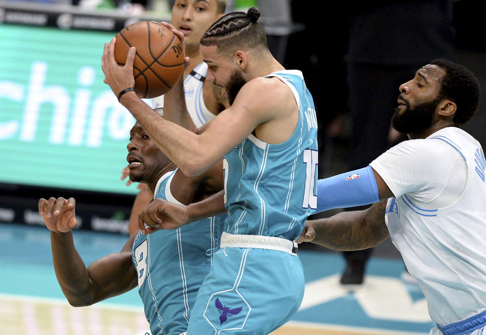 Charlotte Hornets forward Caleb Martin, center, grabs control of a rebound with teammate and center Bismack Biyombo, left, as Los Angeles Lakers center Andre Drummond, right, looks on during the first half of an NBA basketball game in Charlotte, N.C., Tuesday, April 13, 2021. (Jeff Siner/The Charlotte Observer via AP)