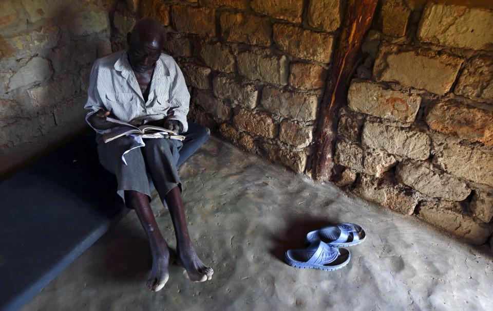 Un hombre seropositvo de 71 años, llamado Sylverio Hachiploa, lee en su cabaña con techo de paja durante la visita de un equipo de atención domiciliaria en Nedwmba, en Zambia.