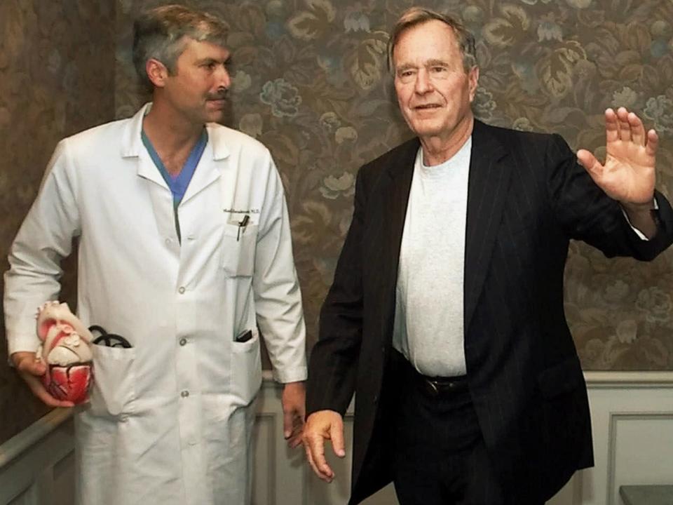 In this 25 February 2000 file photo, former President George HW Bush waves as he leaves Methodist Hospital with his cardiologist, Mark Hausknecht, who was killed in a bicycle drive-by shooting on 20 July 2018: AP Photo/David J. Phillip, File