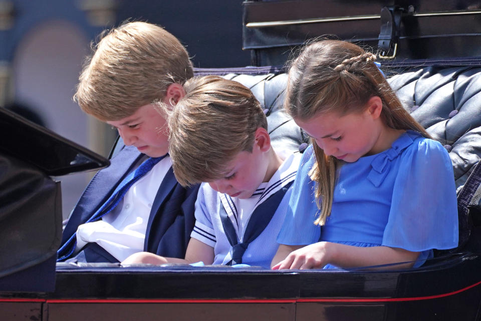 LONDON, ENGLAND - JUNE 02: (L-R) Prince George of Cambridge, Prince Louis of Cambridge and Princess Charlotte of Cambridge bow their heads as they receive a salute as the Royal Procession returns to Buckingham Palace during the Trooping the Colour parade the Trooping the Colour parade on June 2, 2022 in London, England. Trooping The Colour, also known as The Queen's Birthday Parade, is a military ceremony performed by regiments of the British Army that has taken place since the mid-17th century. It marks the official birthday of the British Sovereign. This year, from June 2 to June 5, 2022, there is the added celebration of the Platinum Jubilee of Elizabeth II  in the UK and Commonwealth to mark the 70th anniversary of her accession to the throne on 6 February 1952. (Photo by Jonathan Brady - WPA Pool/Getty Images)