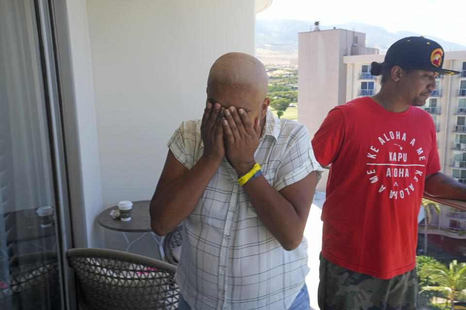 Makalea Ahhee, left, tears up while her husband, JP Mayoga, right, a chef at the Westin Maui, Kaanapali, stand on their balcony at the hotel and resort, Sunday, Aug. 13, 2023, near Lahaina, Hawaii. About 200 employees are living there with their families in the resort. Officials urge tourists to avoid traveling to Maui as many hotels prepare to house evacuees and first responders on the island where a wildfire demolished a historic town and killed dozens of people. (AP Photo/Rick Bowmer)