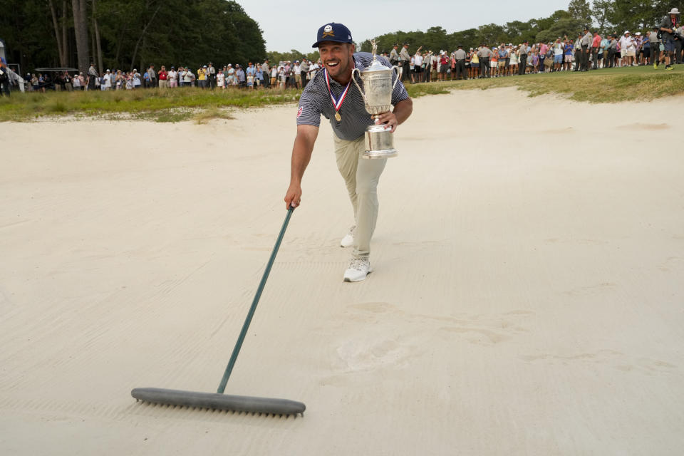 Bryson DeChambeau holds the trophy in the bunker after winning the U.S. Open golf tournament Sunday, June 16, 2024, in Pinehurst, N.C. (AP Photo/Matt York)