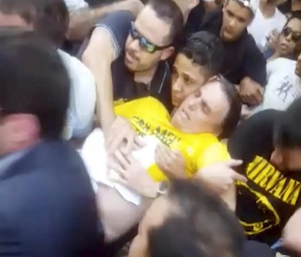 FILE - In this Sept. 6, 2018 video still file provided by Fernando Goncalves, presidential candidate Jair Bolsonaro is carried away after being stabbed during a campaign rally in Juiz de Fora, Brazil. (AP Photo/Fernando Goncalves, File)