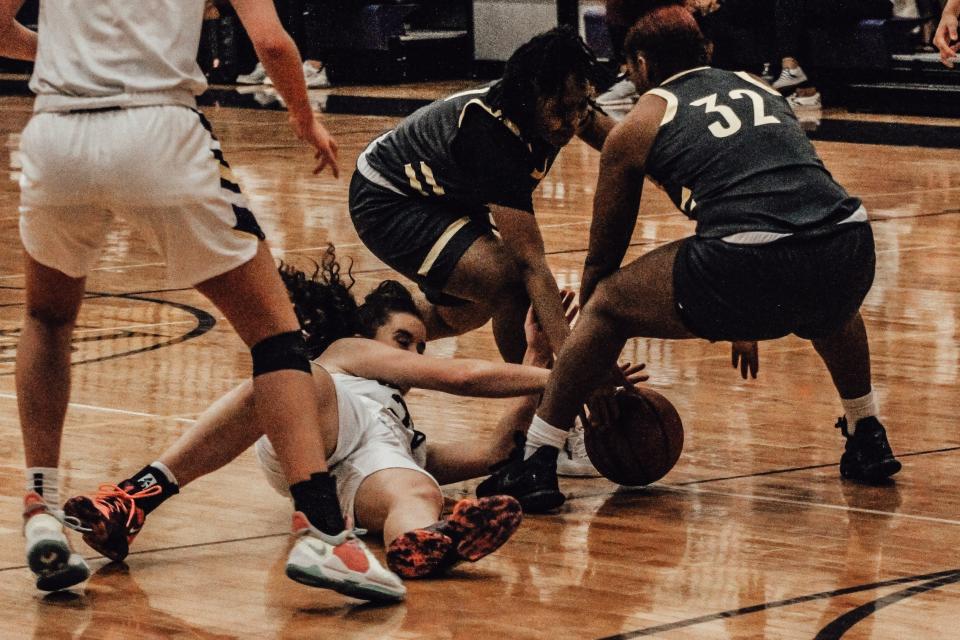 Battle's Me’Ahjai Anderson, center, and Jaleah Brookins (32) try to wrestle the ball away from Hickman's Sophie Elfrink during the Kewpies' 61-53 win over the Spartans on Friday at Hickman High School.