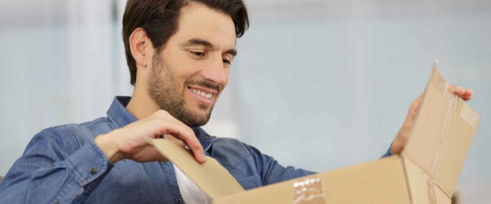 handsome man opening a parcel at home