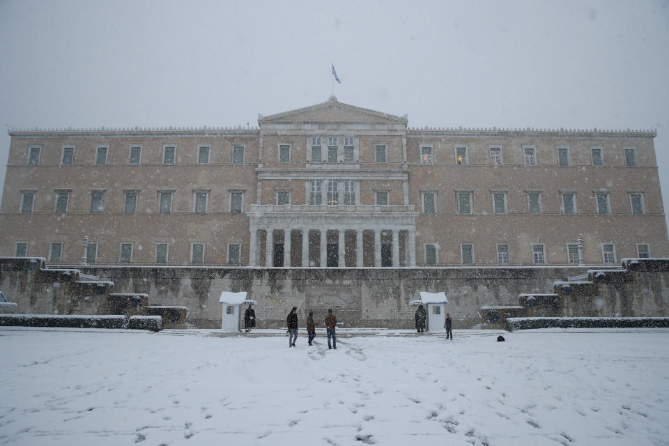 Snow falls in front of the Greek parliament in Athens, Tuesday, Feb. 16, 2021. A cold weather front has hit Greece, sending temperatures plunging from the low 20s Celsius (around 70 Fahrenheit) on Friday to well below freezing on Tuesday, and heavy snowfall in central Athens. (AP Photo/Thanassis Stavrakis)