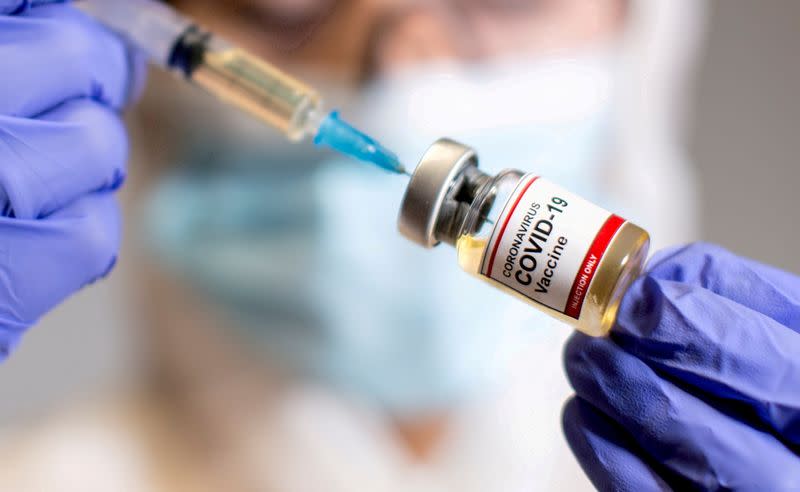 FILE PHOTO: FILE PHOTO: A woman holds a medical syringe and a small bottle labelled "Coronavirus COVID-19 Vaccine