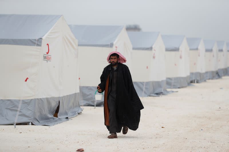 FILE PHOTO: A displaced Syrian man walks past by tents supplied by Turkish Red Crescent at Kelbit camp in Idlib province