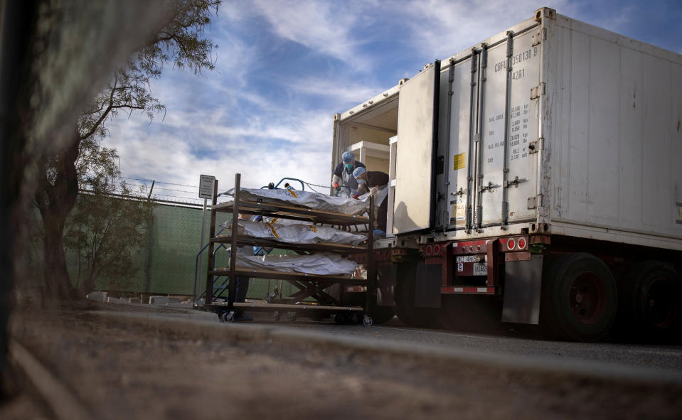 El Paso County Medical Examiner's Office staff help move bodies in bags labeled 