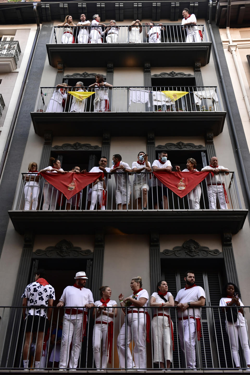 People stand on balconies to watch the running of the bulls at the San Fermin Festival in Pamplona, northern Spain, Tuesday, July 12, 2022. Revellers from around the world flock to Pamplona every year for nine days of uninterrupted partying in Pamplona's famed running of the bulls festival which was suspended for the past two years because of the coronavirus pandemic. (AP Photo/Alvaro Barrientos)