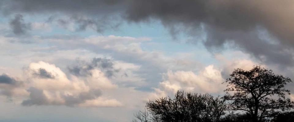 Stormy sky with rain clouds or smoke from a fire black looming clouds of smoke with red reflections and bright white gaps