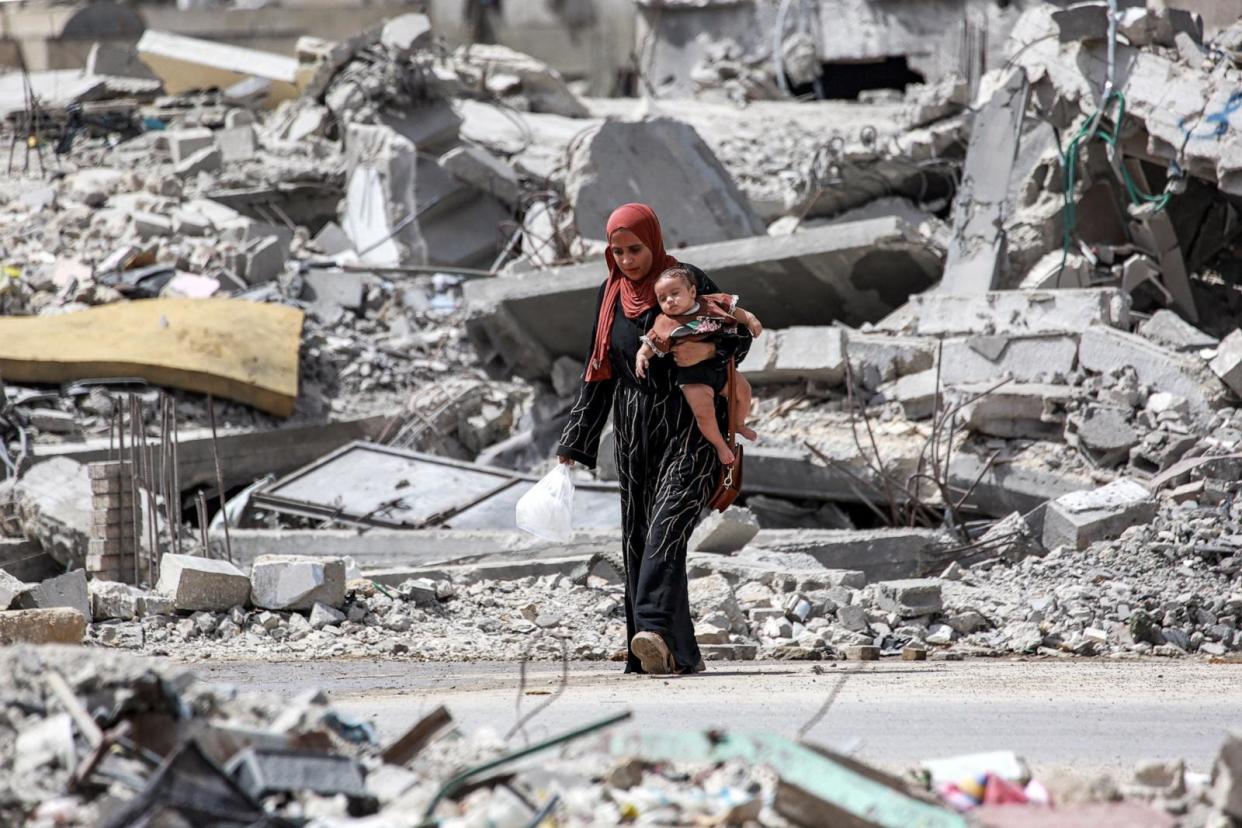 PHOTO: A woman walks with an infant past the rubble of a collapsed building in Khan Yunis in the southern Gaza Strip on September 16, 2024 amid the ongoing war in the Palestinian territory between Israel and Hamas.  (Bashar Taleb/AFP via Getty Images)