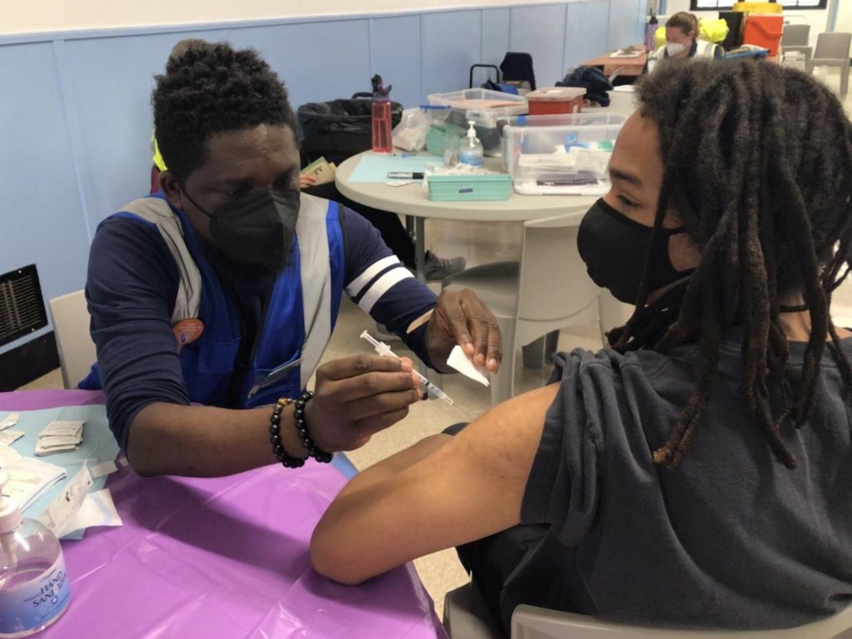 Oluwasegun Abe gives Eli Muhammad, 21, a vaccine dose at a LouVax clinic at Shawnee Community Center on Thursday,  Jan. 13, 2022.