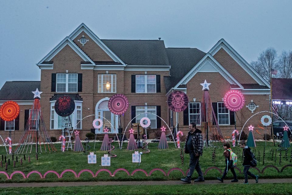 Middletown residents walk in front of Manny Duarte's home and the 31,000 Christmas lights display Duarte mounts each year outside his home in Middletown, Wednesday, Dec. 7, 2022. The lights on display are synchronized to Christmas carols, a project that takes months to put together.