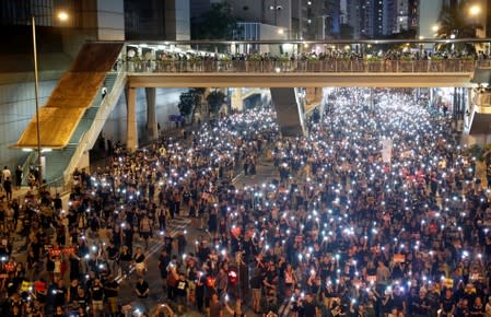 Anti-extradition bill protesters use the flashlights from their phones as they march during the anniversary of Hong Kong's handover to China in Hong Kong