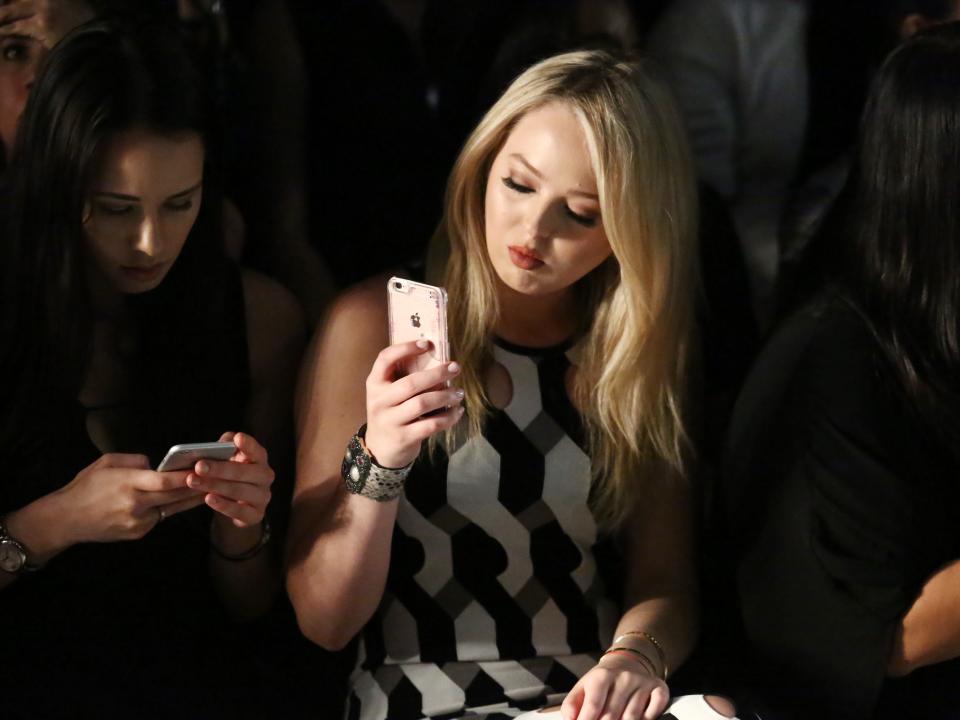 Tiffany Trump takes a photo with her phone at a fashion show