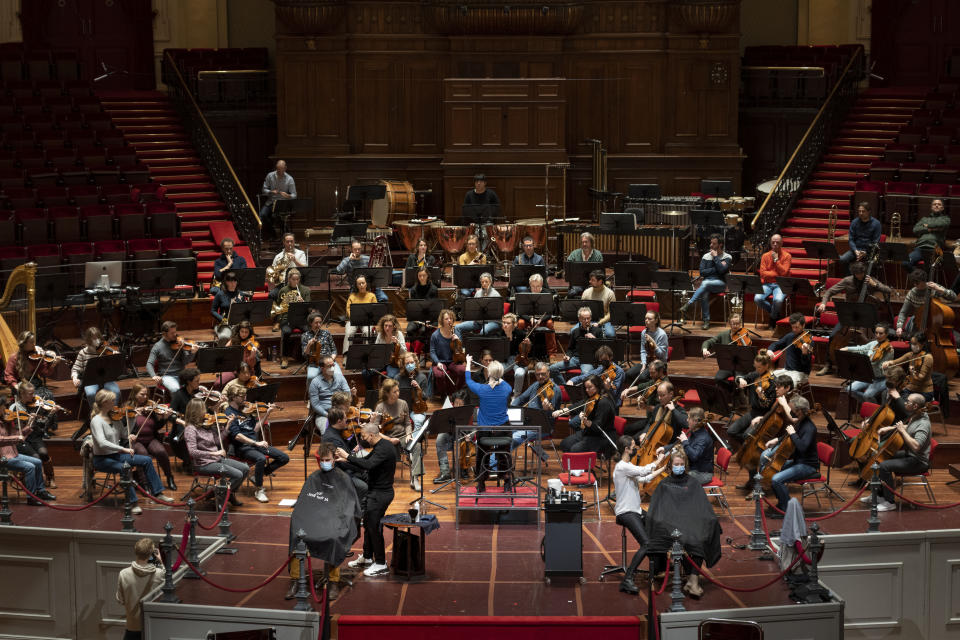 People get a haircut on stage during a rehearsal at the Concertgebouw in Amsterdam, Wednesday, Jan. 19, 2022, as Dutch museums, theaters and concert halls played host Wednesday to businesses that are allowed to open to customers as a protest against their own continuing lockdown closures. (AP Photo/Peter Dejong)