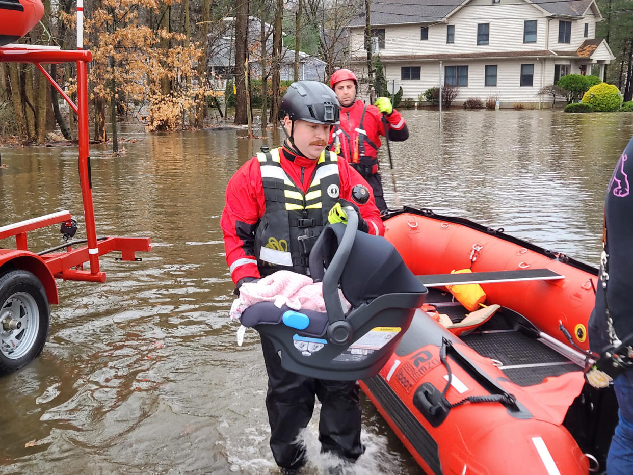 Firefighter and Police Sgt. Matthew Buesser rescues a baby after the family’s home was hit by floods Monday. (Courtesy Captain Sean Smith of the Hillsdale, NJ Fire Department. )