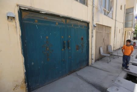 An Afghan boy looks at the entrance gate of a house, where a German aid worker and an Afghan guard were killed last night, in Kabul, Afghanistan May, 2017. REUTERS/Omar Sobhani