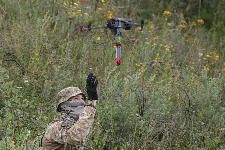 Un voluntario checheno antirruso sostiene un dron armado con un artefacto explosivo en una zona de entrenamiento militar en las afueras de Kiev, Ucrania, el sábado 27 de agosto de 2022. (AP Foto/Andrew Kravchenko)