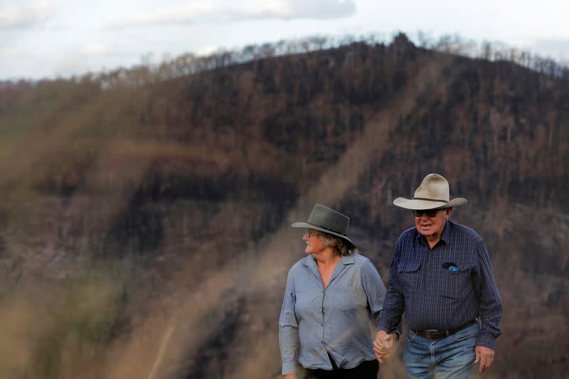 Janice Coates, 66, and her husband John Coates, 76, pose in front of a bushfire affected area on their property in Buchan, Victoria, Australia