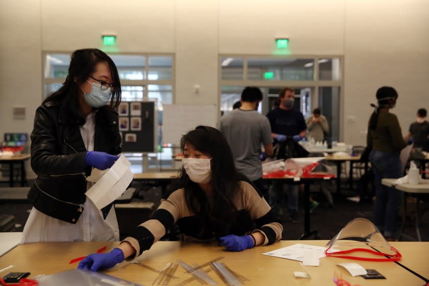 LOS ANGELES, CA - APRIL 19, 2020: Minji Kim, left, and Vivian Hu, right, make face shields with other UCLA students and volunteers to help support doctors on the frontlines of the coronavirus pandemic who may not have enough PPE at Geffen Hall UCLA on April 19, 2020, in Los Angeles, California. He poses on his break. ({Dania Maxwell} / {Los Angeles Times})