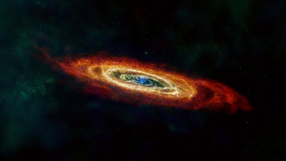 The Andromeda galaxy, or M31, is shown here in far-infrared and radio wavelengths of light. Some of the hydrogen gas (red) that traces the edge of Andromeda’s disc was pulled in from intergalactic space, and some was torn away from galaxies that merged with Andromeda far in the past.