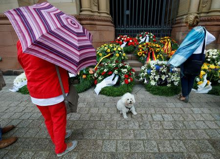 People look at the wreaths laying in front of the Cathedral before the funeral of the late former German Chancellor Helmut Kohl in Speyer, Germany, July 1, 2017. REUTERS/Ralph Orlowski