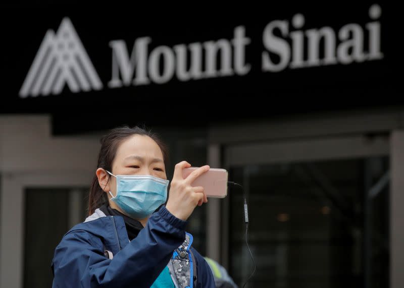 A healthcare worker uses her phone outside at Mount Sinai Hospital hold a protest demanding critical Personal Protective Equipment (PPE) to handle patients during the outbreak coronavirus disease (COVID-19) outbreak, in New York