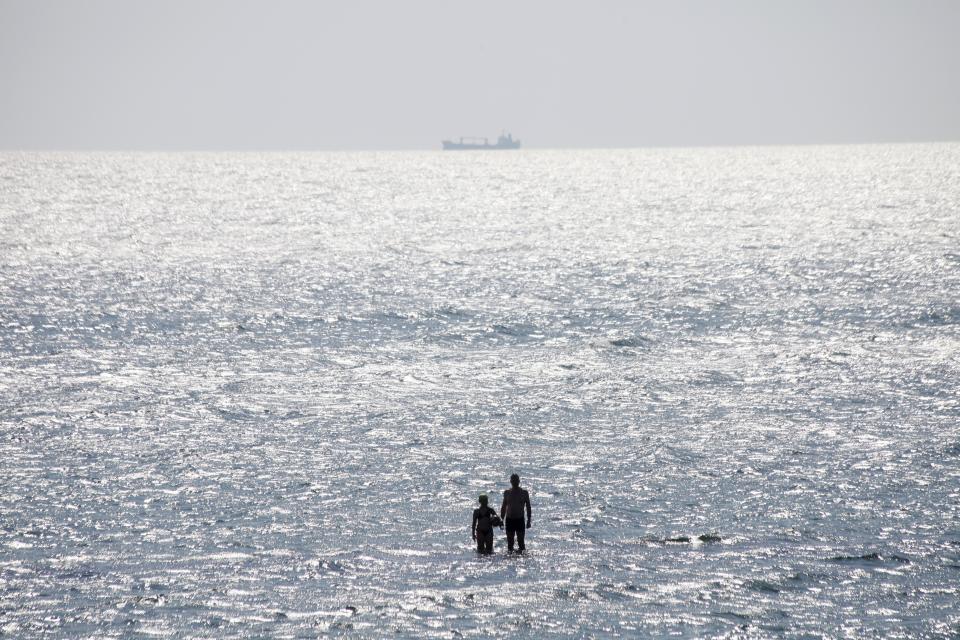 People enjoy the sun at the beach in the Black Sea in Odessa, Ukraine, Sunday, July 5, 2020. Tens of thousands of vacation-goers in Russia and Ukraine have descended on Black Sea beaches, paying little attention to safety measures despite levels of contagion still remaining high in both countries. (AP Photo/Sergei Poliakov)