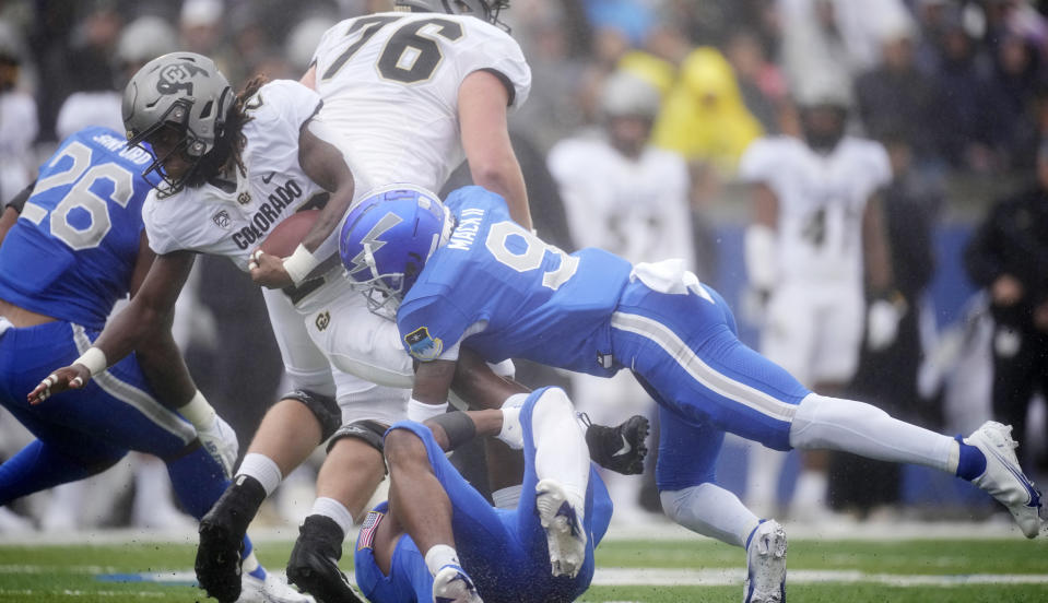 Colorado running back Deion Smith, left, is stopped by Air Force safety Trey Taylor, bottom right, and cornerback Michael Mack II in the first half of an NCAA college football game Saturday, Sept. 10, 2022, at Air Force Academy, Colo. (AP Photo/David Zalubowski)