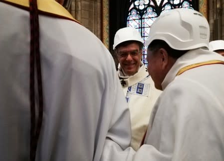 The Archbishop of Paris Michel Aupetit speaks with fellow clergy during first mass in a side chapel two months to the day after a devastating fire engulfed the Notre-Dame de Paris cathedral, in Paris