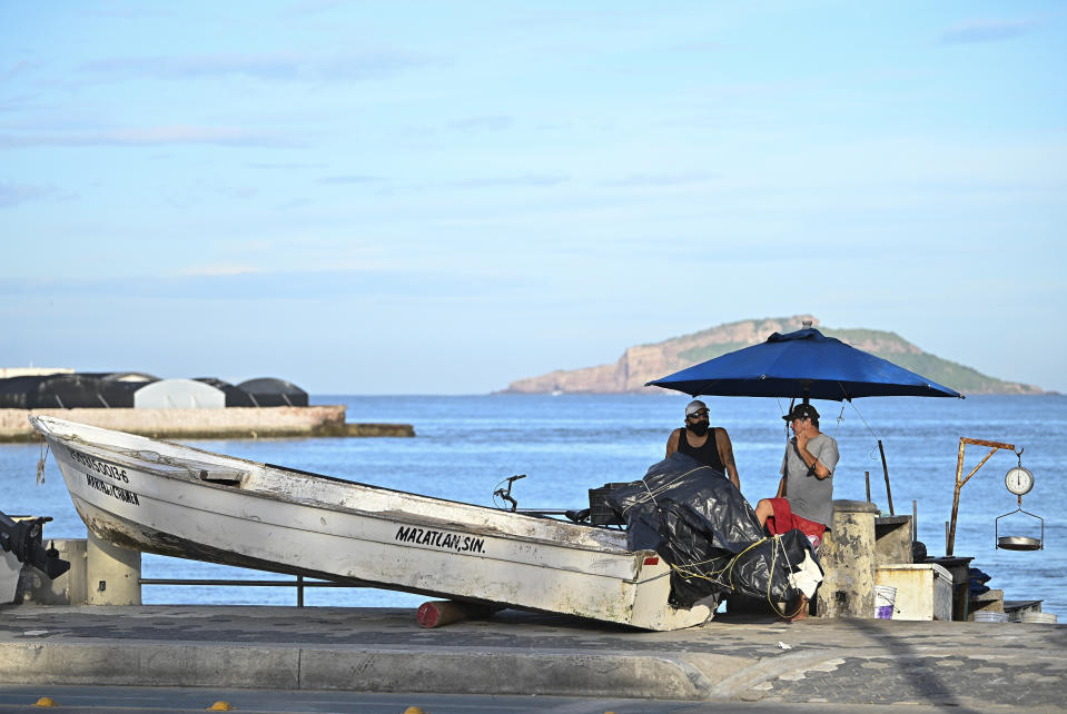 Fishermen talk after lifting their boat on land prior the landfall of tropical storm Pamela, in Mazatlan, Mexico, Tuesday, Oct. 12, 2021. Hurricane Pamela weakened to a tropical storm Tuesday afternoon as it meandered off Mexico's Pacific coast. Forecasters said it was expected to regain strength overnight and be a hurricane when making landfall somewhere near the port of Mazatlan Wednesday. (AP Photo/Roberto Echeagaray)