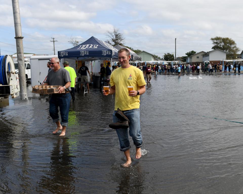 People walk thorugh the flood waters at J. Millard Tawes Crab and Clam Bake Wednesday, Sept. 27, 2023, at Somers Cove Marina in Crisfield, Maryland.