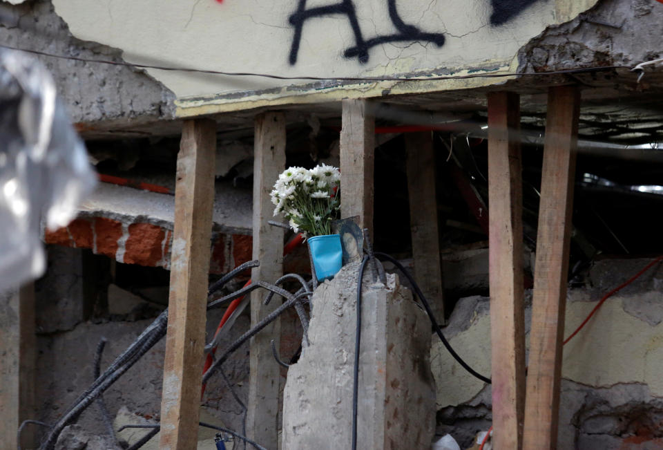 Flowers and a religious image are seen amidst support beams and rubble during the search for students.