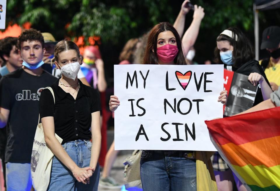 A young woman holds a sign 'my love is not a sin'.