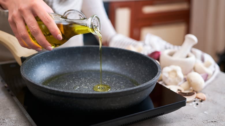 Person adding oil to pan