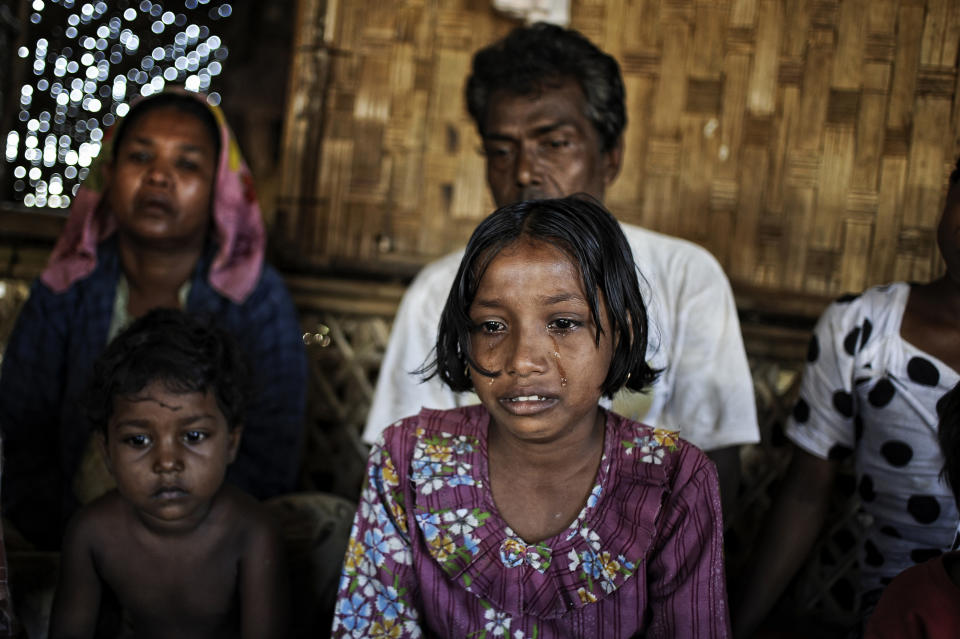 In this Nov. 29, 2013 photo, Tawhera Begum, center, sister of Senwara, cries as she watches a video interview of her sister at the Ohn Taw refugee camp on the outskirts of Sittwe, Myanmar. After their tiny Muslim village in Myanmar's northwest Rakhine had been destroyed in a fire set by an angry Buddhist mob, Senwara, 9, and brother, Mohamed, 15, became separated from the family. (AP Photo/Kaung Htet)